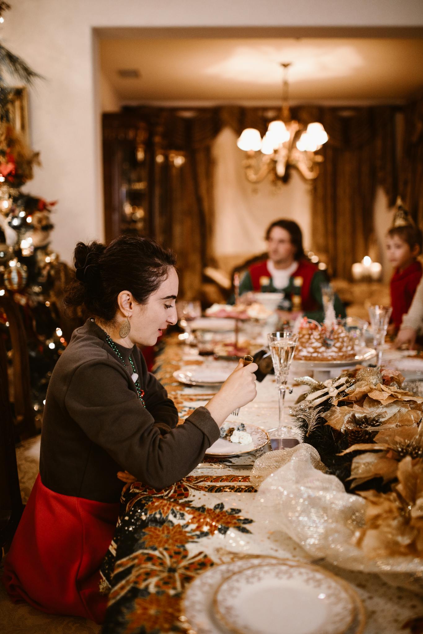 A cozy indoor Christmas dinner setting with friends enjoying a festive meal at a beautifully decorated table.